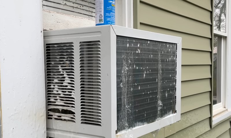 A window air conditioner with a blue can placed on top of it