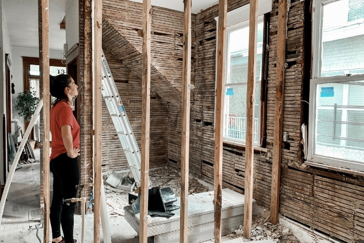 Homeowner inspecting exposed wall studs and framing during an interior wall demolition project.